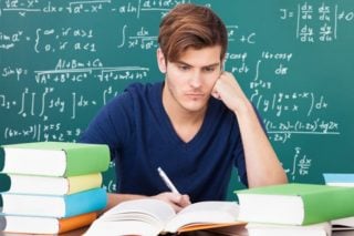 young man studying surrounded by books