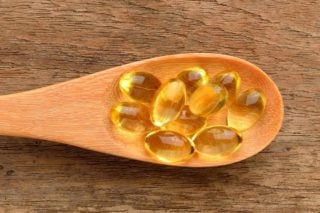 fish oil capsules in a wooden spoon