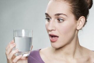 woman looking surprised at a glass of water
