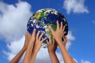 children's hands holding up a globe