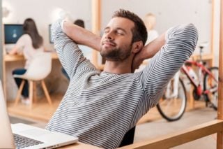 photo of a man looking relaxed sitting in front of his laptop