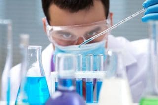 photo of scientist working with beakers and test tubes