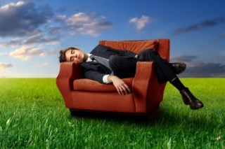 man sleeping in chair in a field of grass
