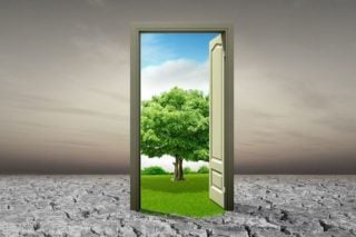 photo of doorway in barren landscape opening on to green field