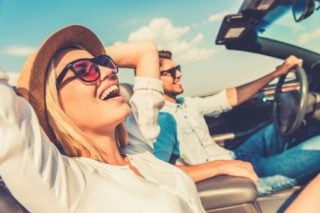 two people riding in convertible, laughing