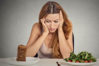 woman trying to choose between healthy and unhealthy foods