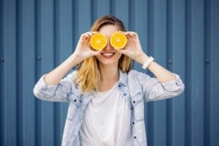woman holding orange slices in front of her eyes