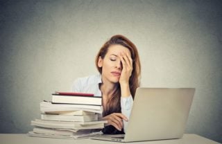 tired woman with books and laptop